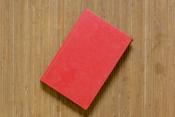 A red book on a mat of a brown color