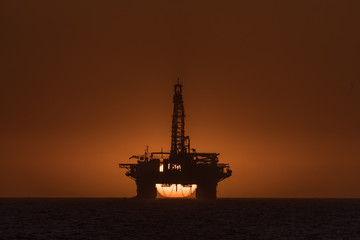 Sun setting behind oil drilling platform at Longbeach in Namibia