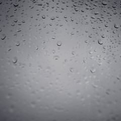 Drops of rain on a grey window glass. Close up   detail of a wet surface water with copy space