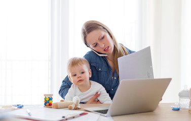 Mother with child in her lap working on computer from home