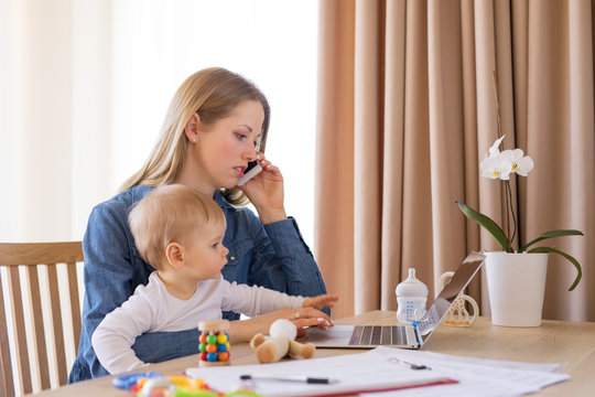 Mother working at home with child in her lap