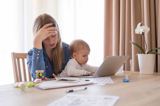 Tired working mom with child in her lap feeling exhausted