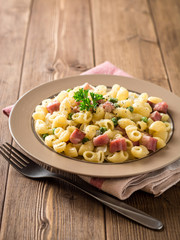 Pasta with green peas, onion, bacon and cheese on wooden background
