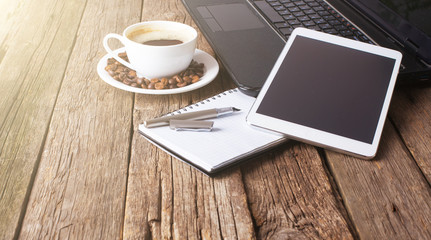 office table with notebook, computer keyboard, mouse, cup of coffee, tablet pc and smartphone. copy space