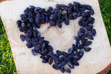 Prunes in shape of heart on wooden background, top view.