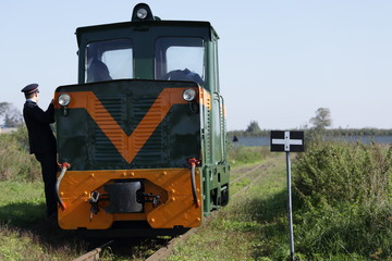 Old locomotive driver and conductor maneuvers on rail tracks. Narrow-gauge railway.