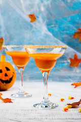 Autumn pumpkin martini cocktail with halloween decor on wooden table. Copy space
