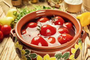 Pickled tomatoes with dill and garlic,herbs with bowl,Preserving fresh and pickled tomatoes, spices and garlic on a wooden table. Home canned vegetables.Homemade tomatoes preserves. Canned tomatoes.