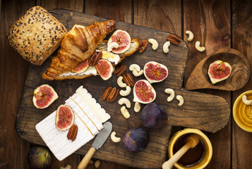 breakfast. a croissant with figs and honey. brie cheese and nuts. wooden board. Vintage background. brown photo. family breakfast. homemade baking