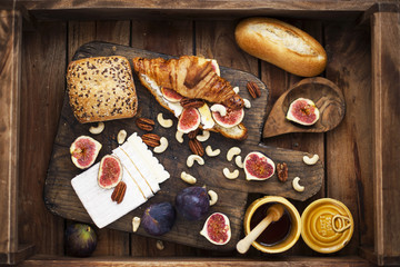 breakfast. a croissant with figs and honey. brie cheese and nuts. wooden board. Vintage background. brown photo. family breakfast. homemade baking
