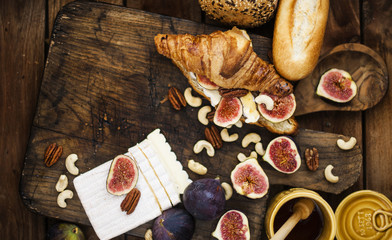 breakfast. a croissant with figs and honey. brie cheese and nuts. wooden board. Vintage background. brown photo. family breakfast. homemade baking