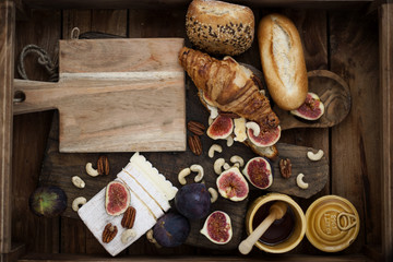 breakfast. a croissant with figs and honey. brie cheese and nuts. wooden board. Vintage background. brown photo. family breakfast. homemade baking