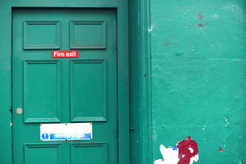 Fachada con puerta trasera de edificio pintada en verde.