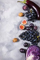 Fresh organic raw purple colored vegetables and fruits on stone background. Top view. Copyspace.