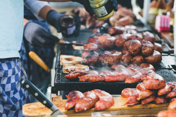 Street food in Amsterdam on sunday market. The cook is doing toasts with fried sausages and mustard.