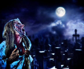 Fototapeta na wymiar Undead zombie scary girl on halloween graveyard at night on dark clouds sky background. Woman in zombie apocalypse hunting outdoor. Behind monster cemetery with crosses. Moon comes out from clouds