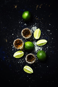 Naklejka Golden mexican tequila with lime and sea salt, black background, top view