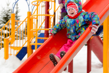 A little girl riding a roller coaster on the Playground in winter