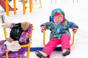 Girl with little sister play on the Playground in winter