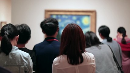 People looking at a work of art. Public starring at a painting at a museum. Group of people contemplating a work of art