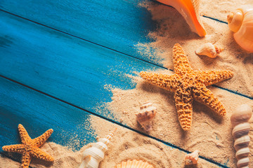 beach scene concept with sea shells and starfish on a blue wooden background