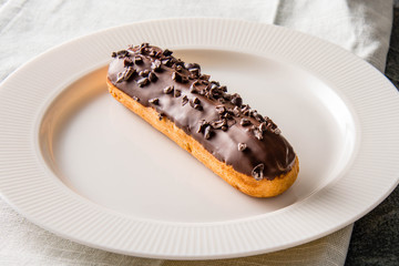 Elegant french chocolate eclairs decorated with chocolate shiny glaze and cocoa beans.