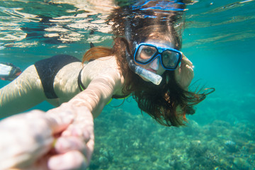 Snorkelling woman in yellow bikini makes tempting gesture in ocean