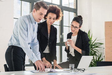 Employees checking together the printed files of a folder with documents and business reports in the office