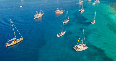 Aerial view of group of sailing boats anchoring on buoys.