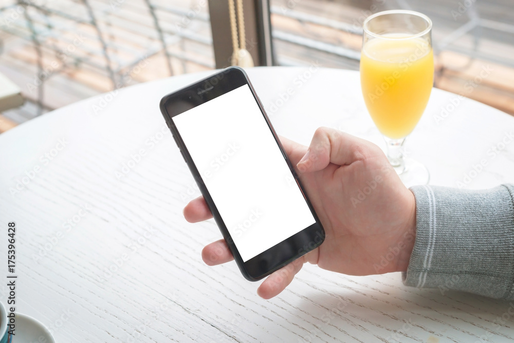 Poster man show modern smart phone with isolated screen for mockup. white wooden desk and juice in backgrou