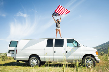 Woman holding American flag on van roof
