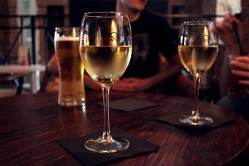Two glasses of white wine and a mug of lager beer on a wooden table