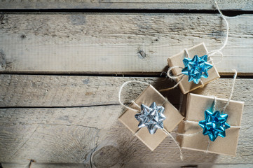Three craft cardboard  gift boxes on a rustic wooden background. Gift kraft boxes with ribbon bow and rope.