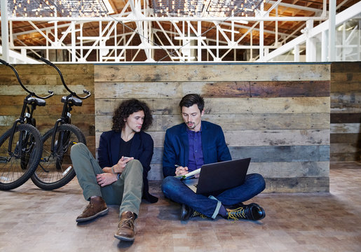 Two millennials meeting on the floor at high tech office