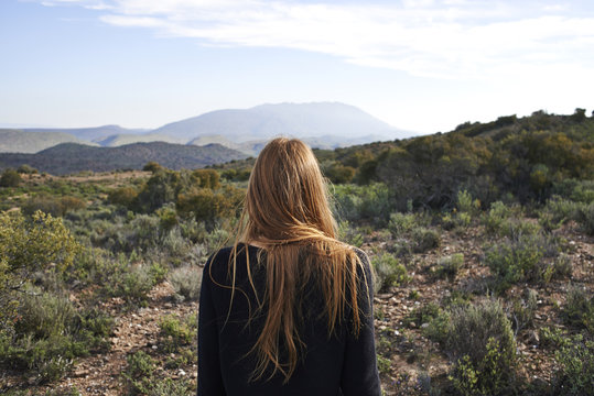 Young Red haired female overlooking a vegetated landscape