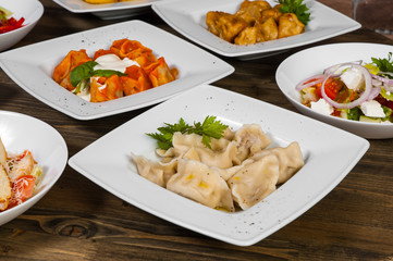 Set of different salads, dumplings and ravioli on a wooden table