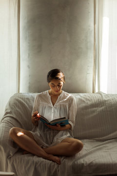 Woman sitting on a couch reading a book
