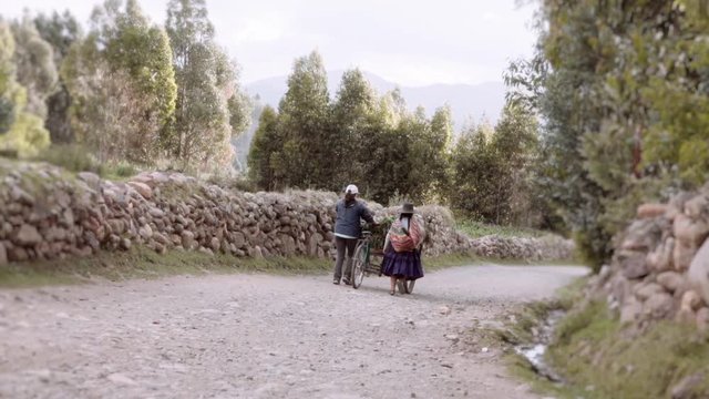 Couple of old Bolivian farmers walking on a dirt path wearing traditional costumes