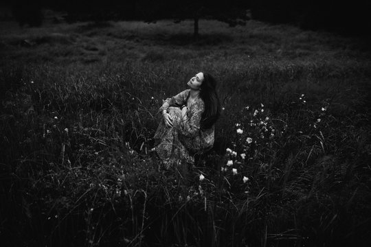 Black and white Romantic image of woman sat in a meadow.