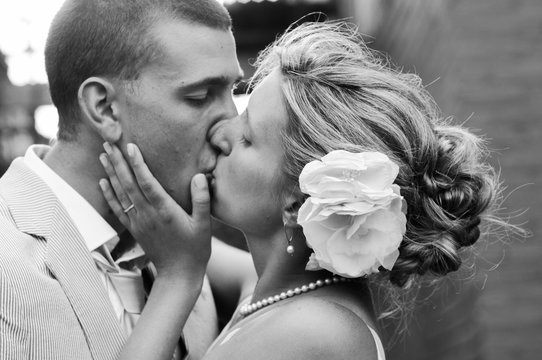 A black and white portrait of a bride and groom kissing on their wedding day