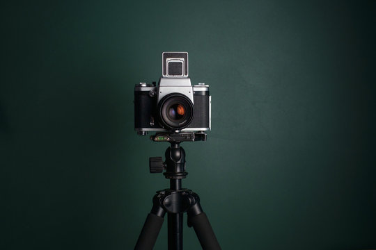 Medium format camera on tripod against green background