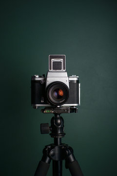 Medium format camera on tripod against green background