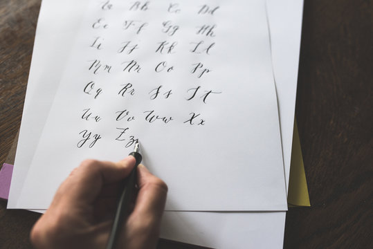 A Left Handed Person Writes The Alphabet With A Straight Calligraphy Pen