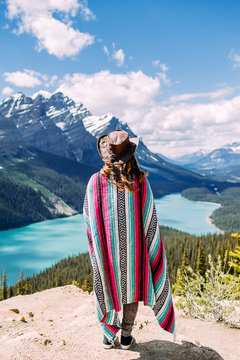A woman standing on a mountain looking down a the blue waters of a lake