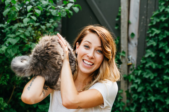young woman trying to hold on to cat while it jumps out of her arms