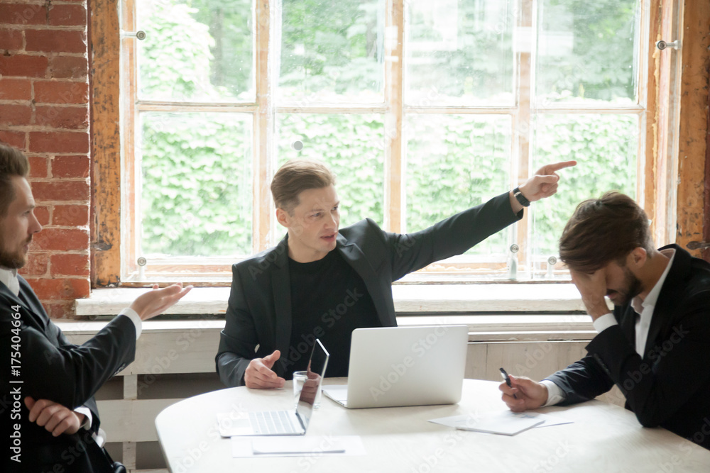 Wall mural strict boss, telling upset male employee to leave meeting room during briefing, pointing his finger 