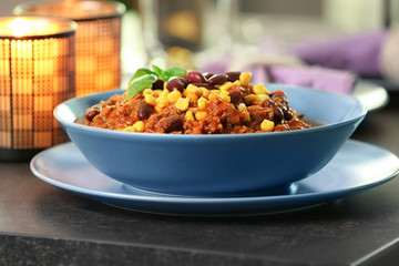 Bowl with delicious chili con carne on served table
