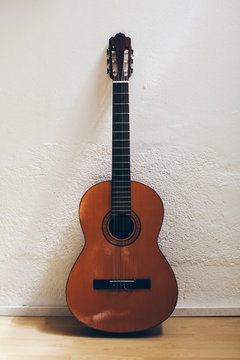 Spanish acoustic guitar standing on a white wall.