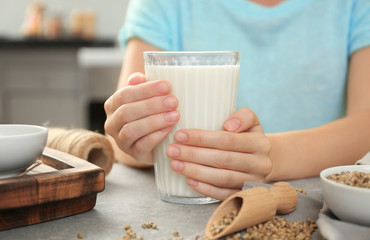 Woman holding glass with hemp milk at table