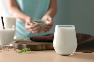 Glass with hemp milk and blurred woman on background